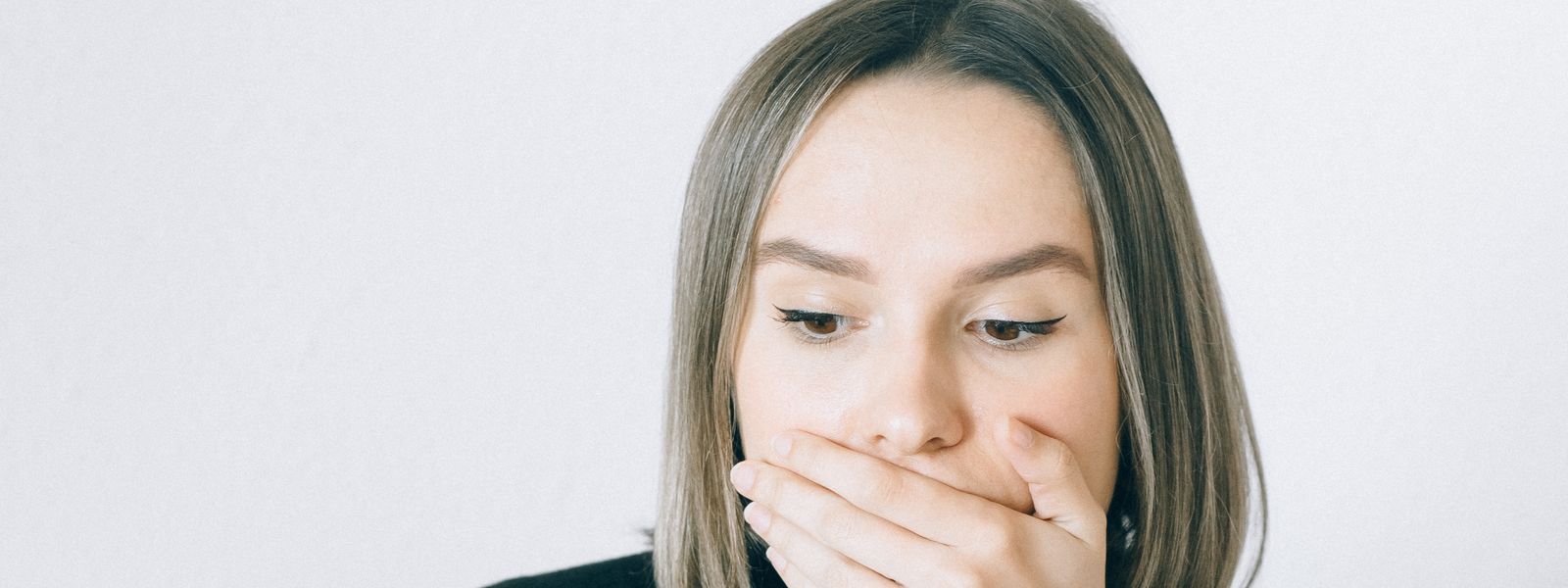 A woman covering her mouth with her hand in shock as she reads a financial document