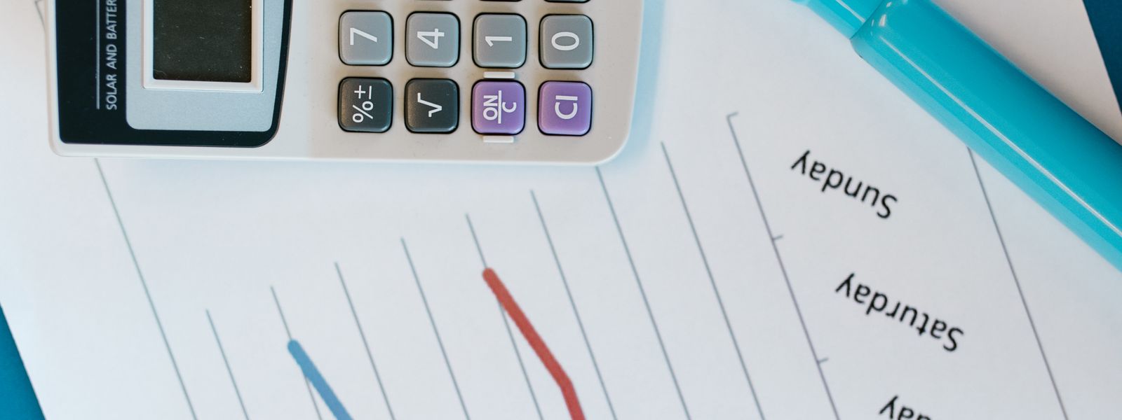 Calculator resting on a printed weekly Monday-to-Sunday sheet beside a blue highlighter pen