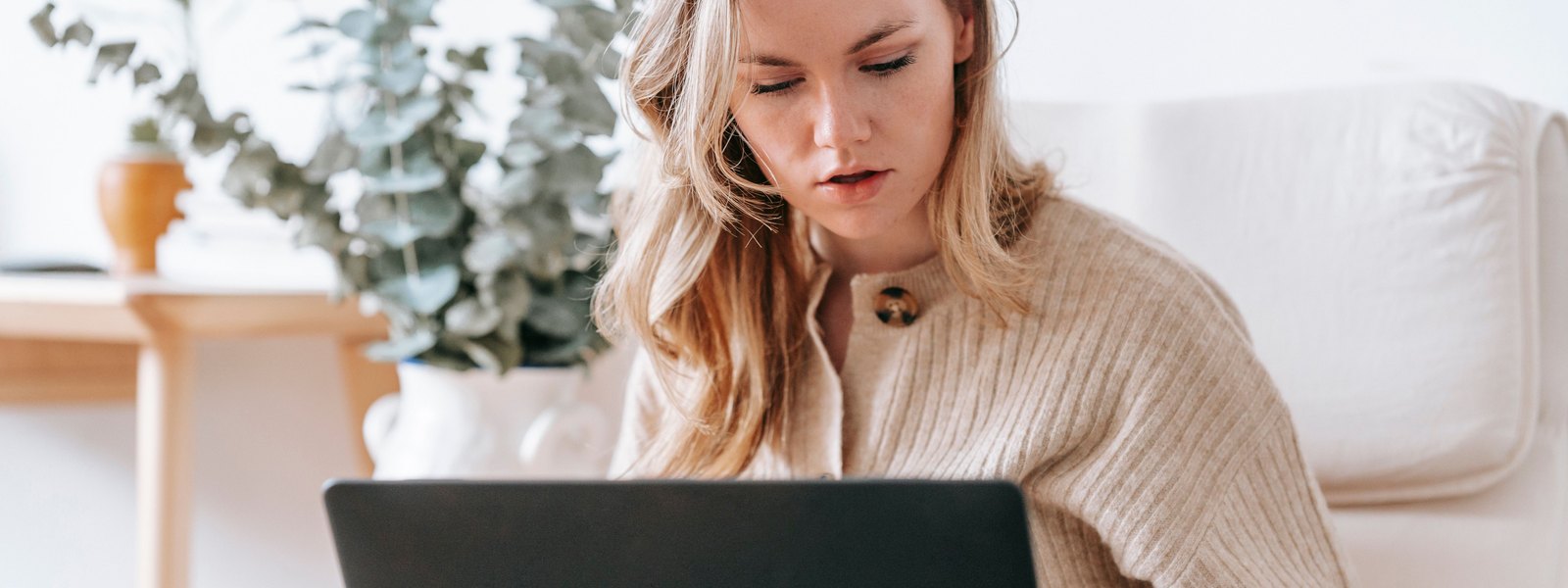 An independent contractor working on a laptop at a home-office desk with a notebook and coffee